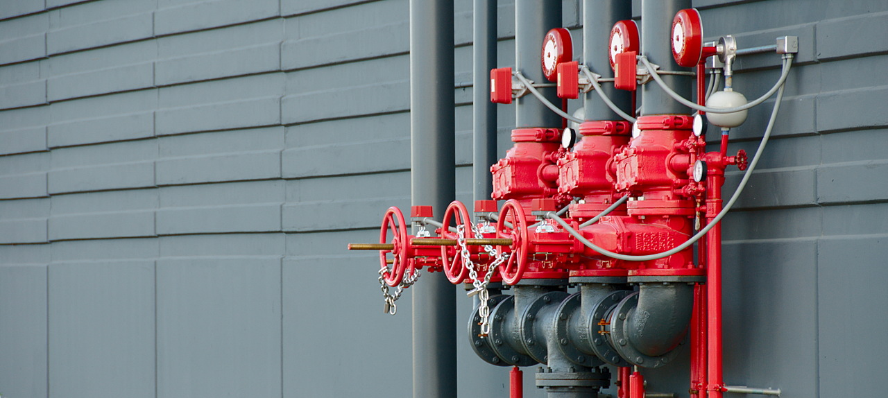 Red industrial piping on side of gray building